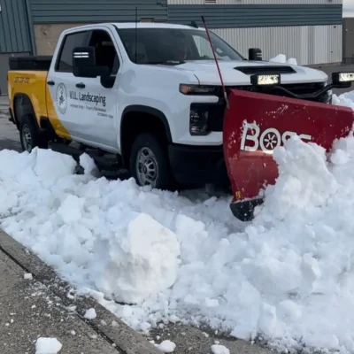 Truck using snowplow to clear snowy street.