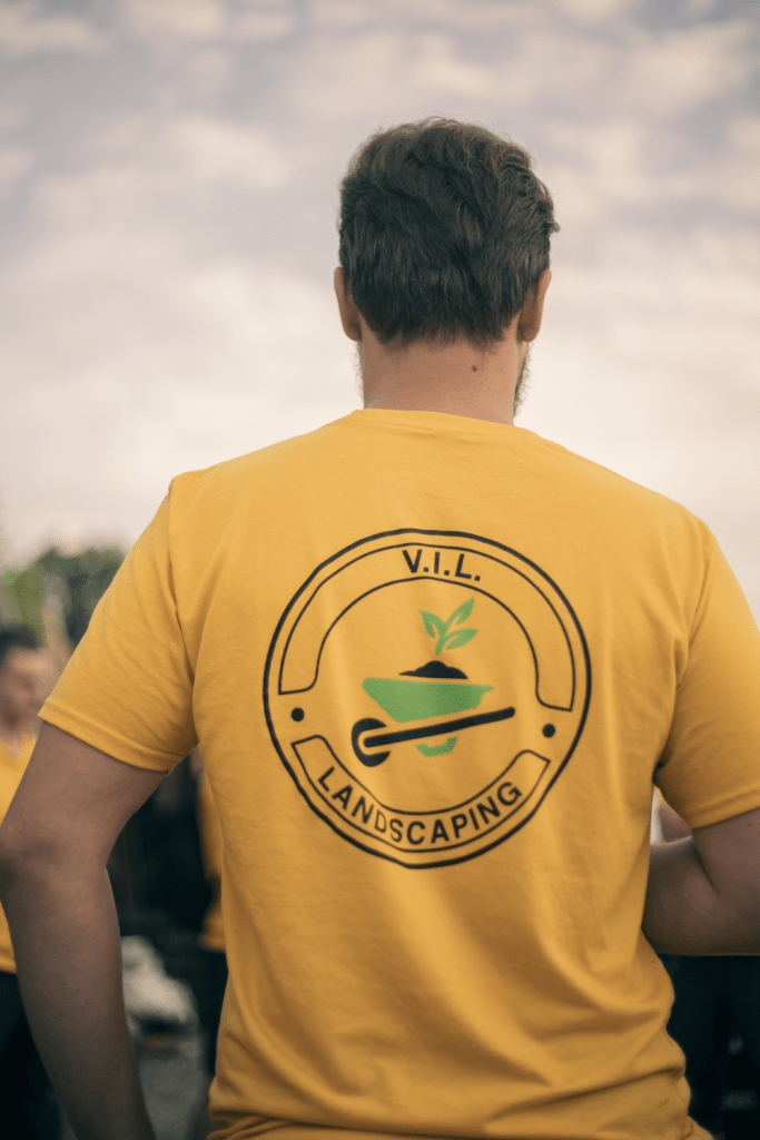 Person wearing yellow V.I.L. Landscaping shirt