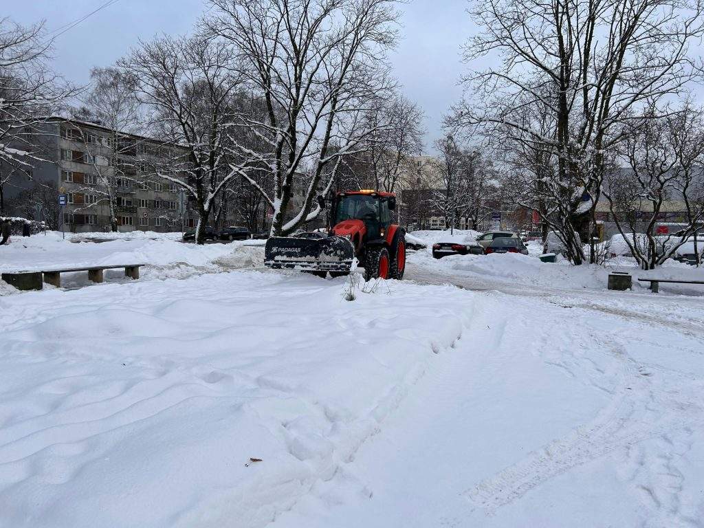 Snowplow clearing snowy street in residential area.